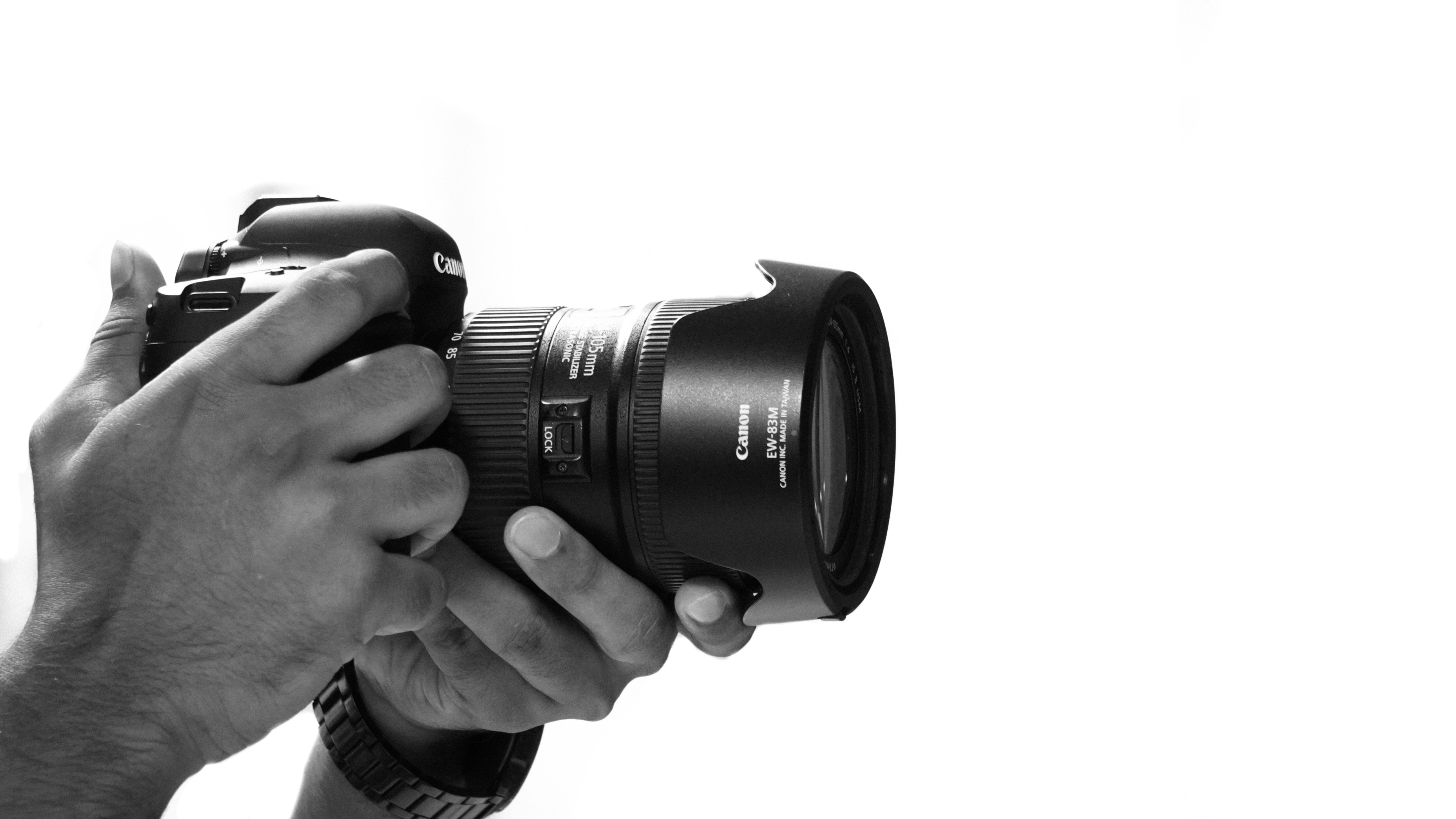 한 손으로 미러리스 카메라를 들고 피사체를 향하는 모습 — 왼손으로 렌즈를 받치는 올바른 자세
