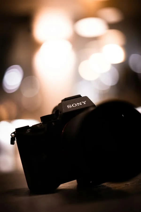 Sony 미러리스 카메라 실루엣과 배경의 따뜻한 보케 조명 — 소프트하고 확산된 빛의 질감